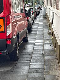 Autos parken den Gehweg zu.