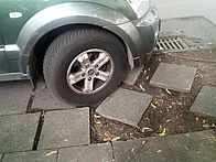 Auto parkt auf Gehweg, der dadurch beschädigt ist.